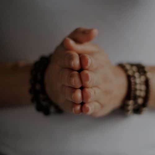 Two hands holding each other with bracelets on them.
