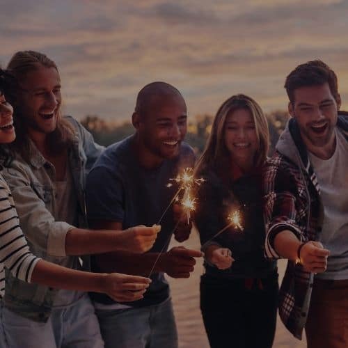 A group of people standing around each other holding sparklers.
