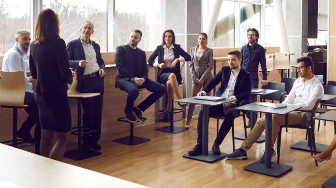 A Group Of People Sitting In Front Of Tables.