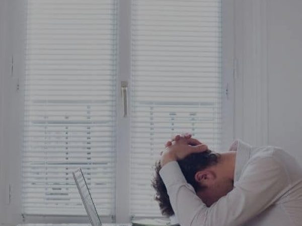 A man sitting at a desk with his head on his hands.