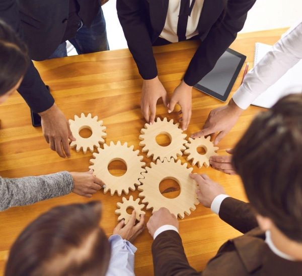 A group of people holding up wooden gears.
