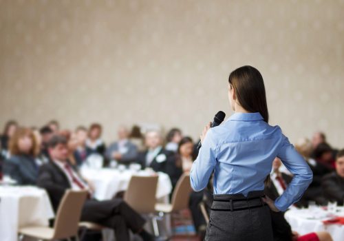 A woman is speaking to an audience at a conference.